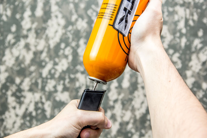 Ajustar o ângulo do green gas para carregar o magazine Magazine de pistola green gas sendo carregado com um cilindro green gas